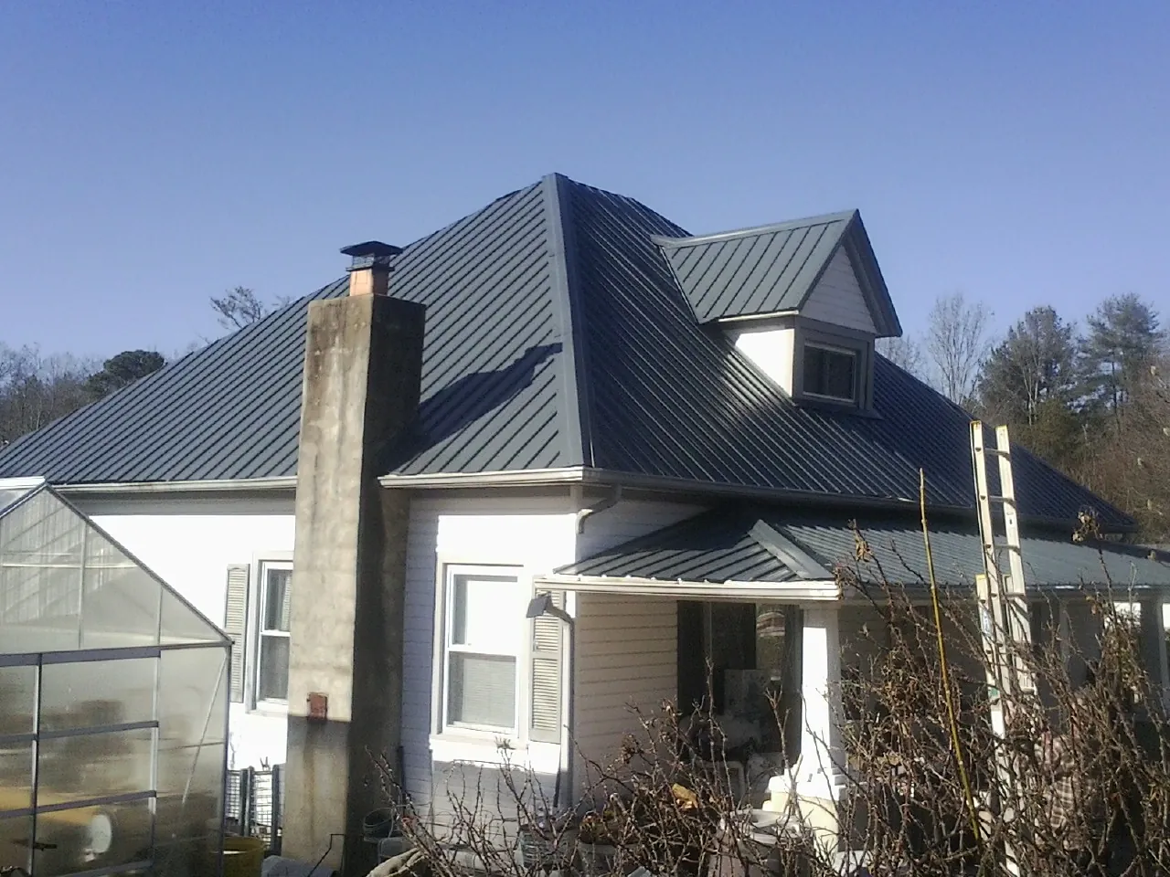 Dark blue standing seam metal roof on a white farmhouse with dormer — Slate & Tile Roof Repair by Roofing Brothers in Sinai