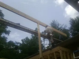 Carpenter setting a ridge beam over a new addition frame — Ice Dam Removal by Roofing Brothers in Sinai