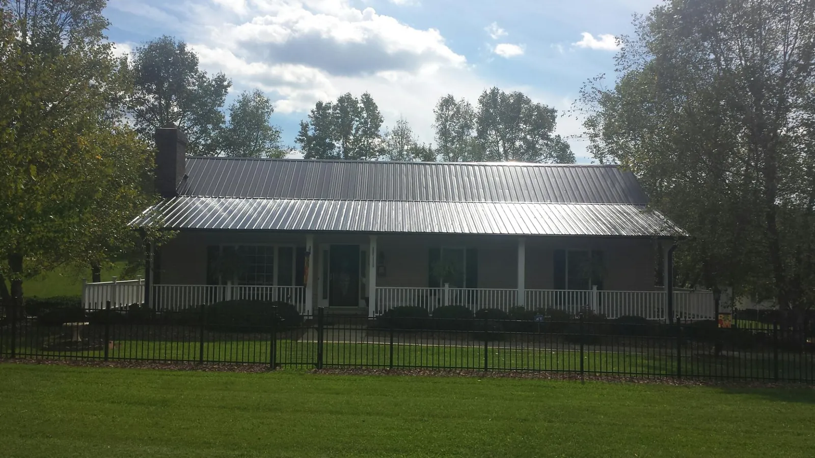 Gray metal roof on a brick ranch with a full width front porch — Gutter Guard Installation work by our crew in Sinai