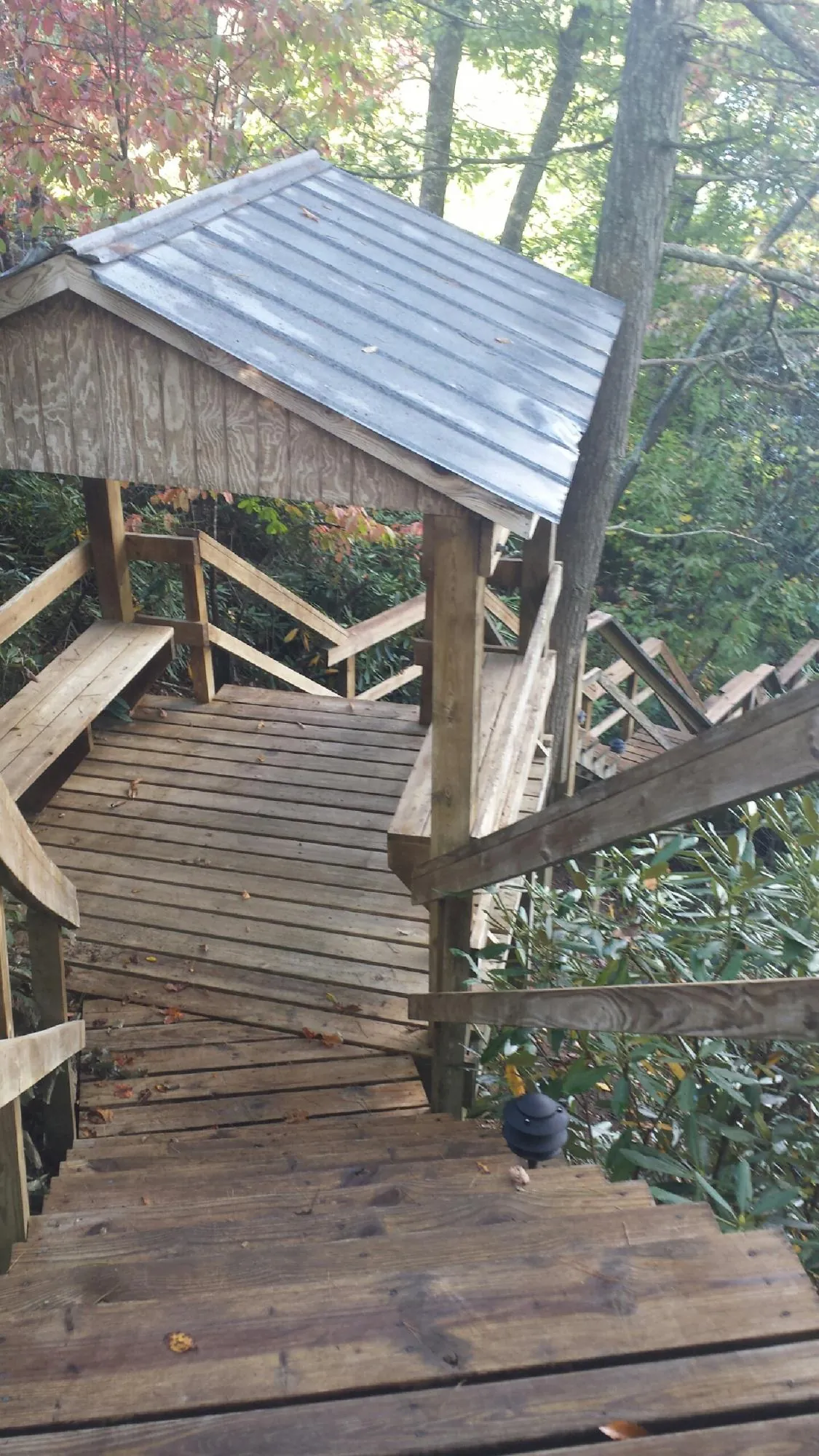 Metal roofed shelter over wooden steps on a wooded walkway — Skylight Repair & Installation work by our crew in Sinai