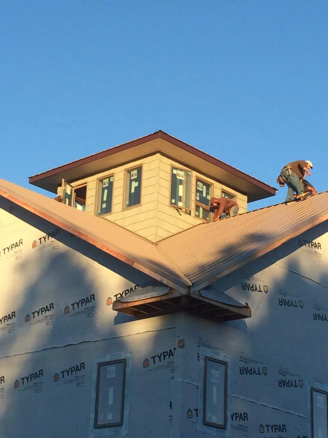 Roofers working around a rooftop cupola on a new metal roof at sunset — Roof Waterproofing in Sinai by Roofing Brothers